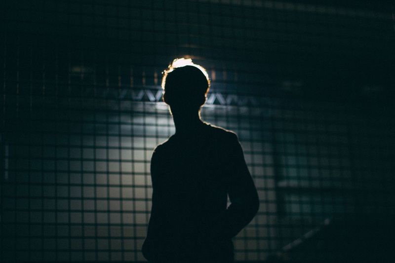 Silhouette man standing against illuminated light