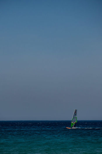 Sailboat in sea against clear sky