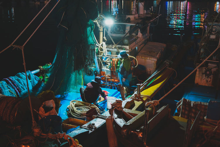 High angle view of fishermen on boat at harbor during night