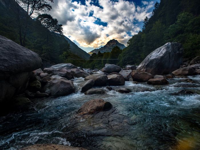 River flowing through rocks against sky