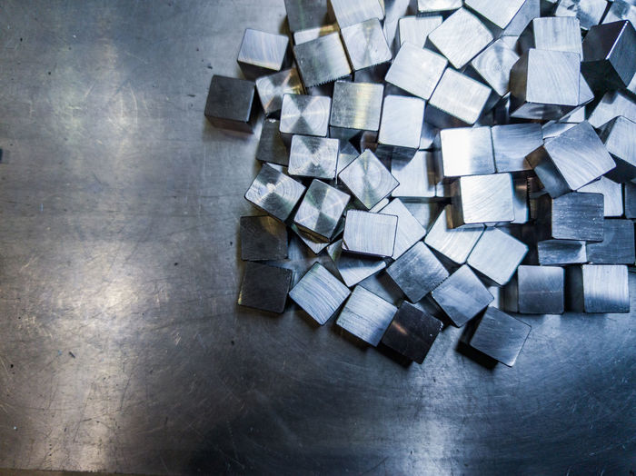 Pile of small machined shiny steel cubes on metal surface