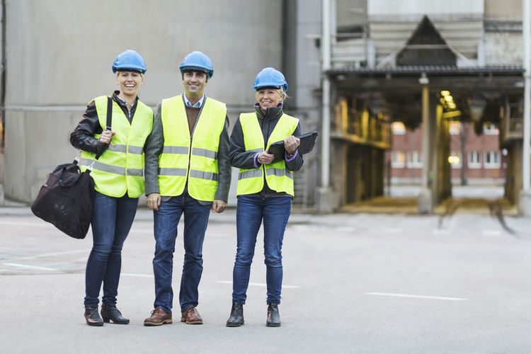 Full length portrait of happy manual workers at factory