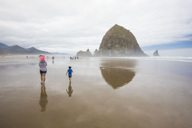 Rear view of mother and two kids walking on cannon beach.