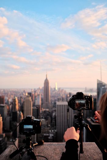 Close-up of woman photographing cityscape against sky