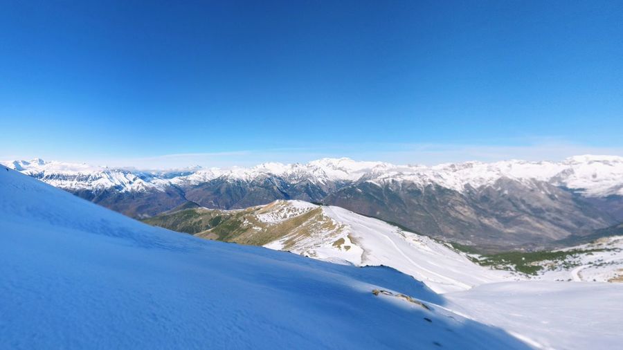 Scenic view of snowcapped mountains against blue sky