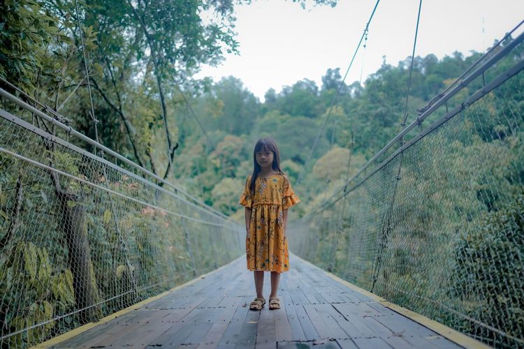 A little asian girl is walking on situ gunung suspension bridge