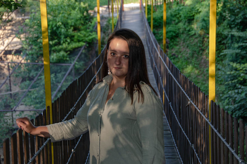 Portrait of young woman standing on bridge