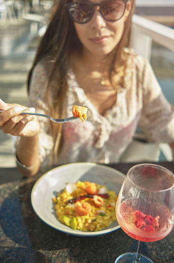Beautiful young girl tasting a delicious risotto with smoked salmon