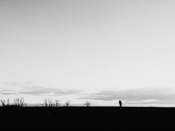Silhouette men standing on landscape against sky