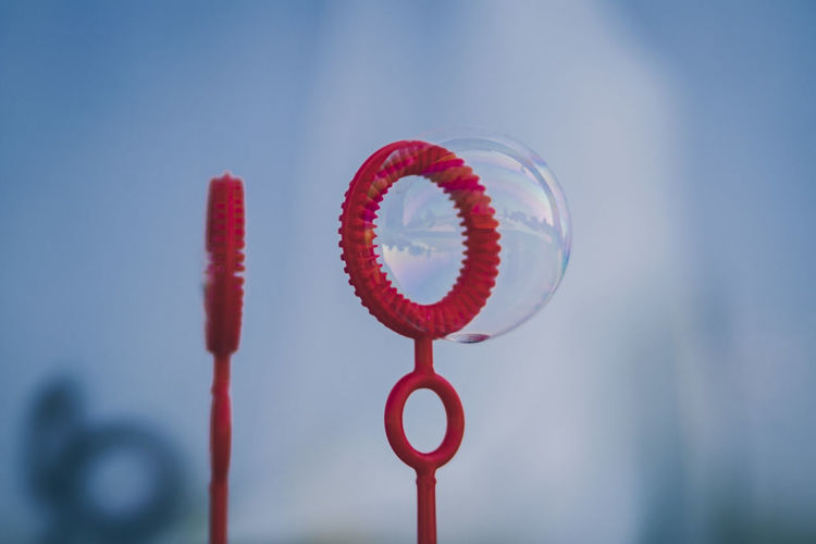 Close-up of red bubble wand against sky