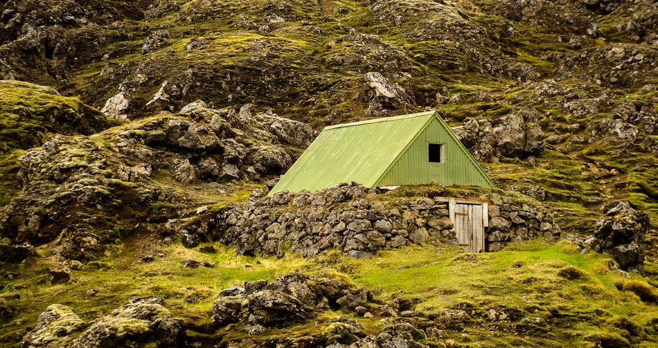 Icelandic hiking lodge small cabin situated in rough wall of rock green moss boulders