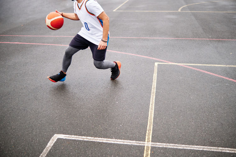Cropped image of male playing basketball at a court outdoors. copy space.