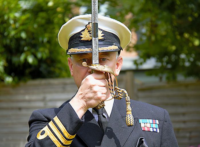 Portrait of army man holding sword standing outdoors