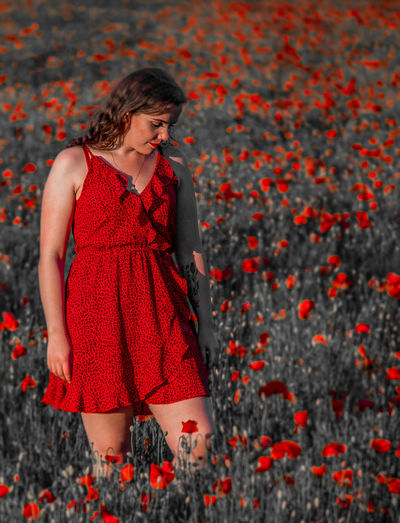 Full length of woman standing against red plants