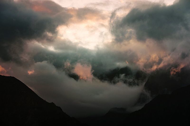 Scenic view of clouds over silhouette mountains against sky