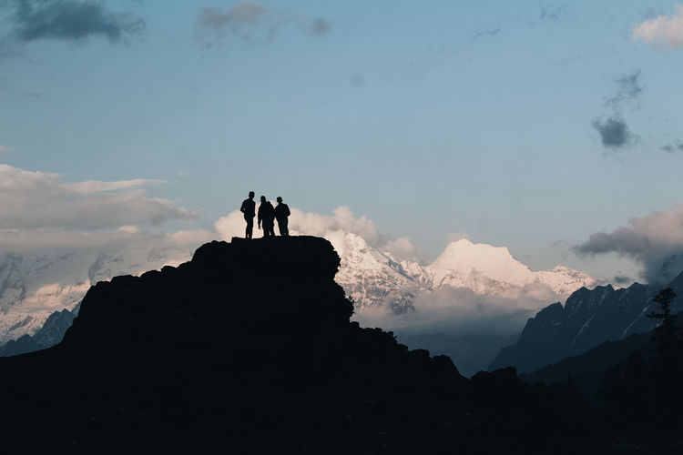 Low angle view of silhouette people standing on mountain against sky