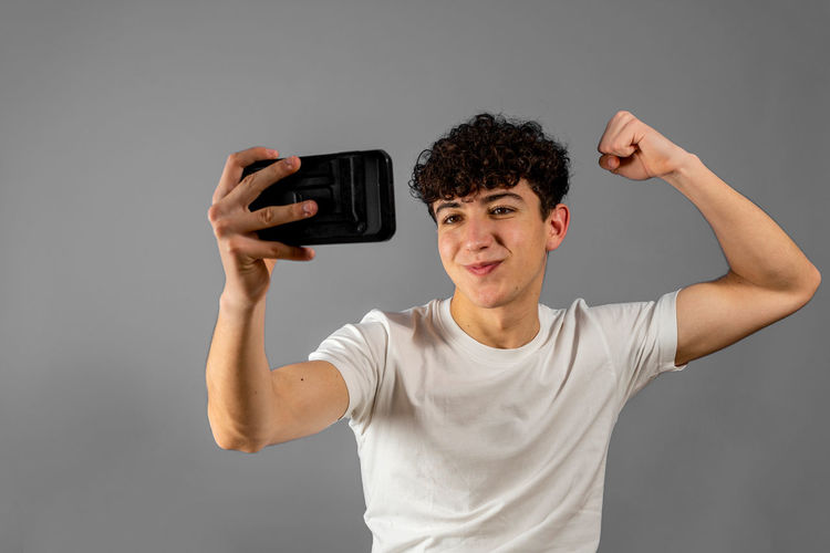 Portrait of young man using smart phone against gray background