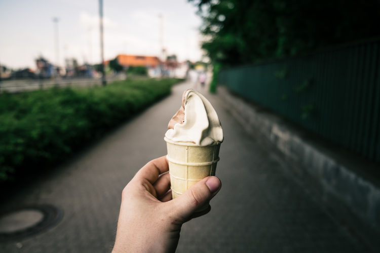 Cropped hand of person holding ice cream on street
