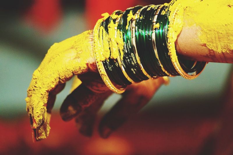 Cropped image of hands covered with turmeric paste during wedding ceremony