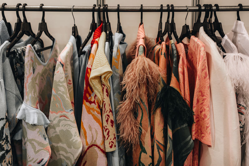 Designer fashion outfits hanging in a row at the backstage of fashion week
