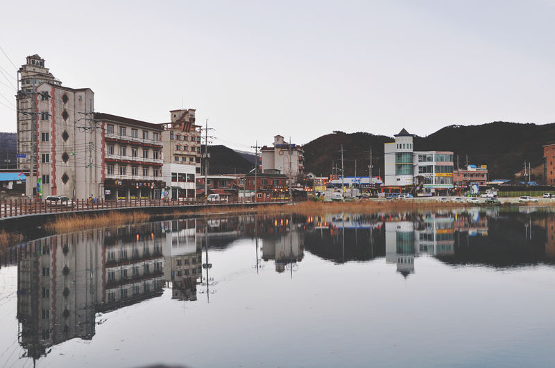 Reflection of buildings in city against clear sky