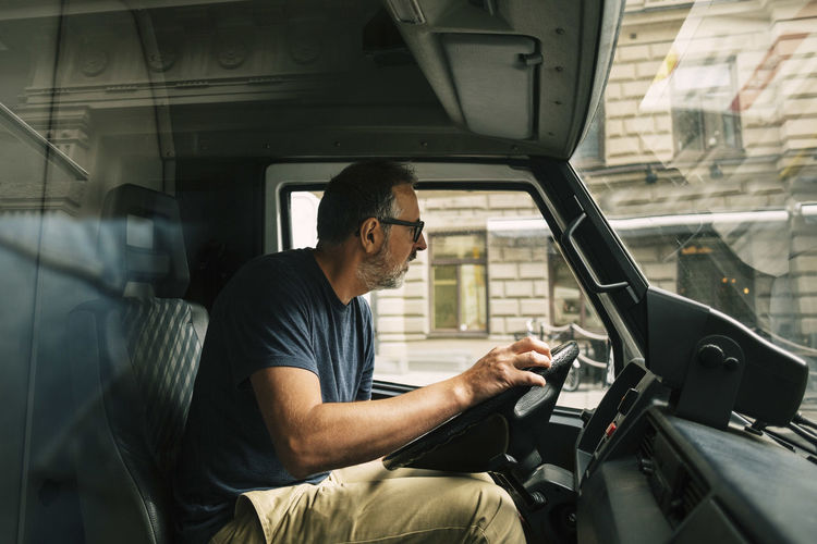 Mature man looking away while driving food truck