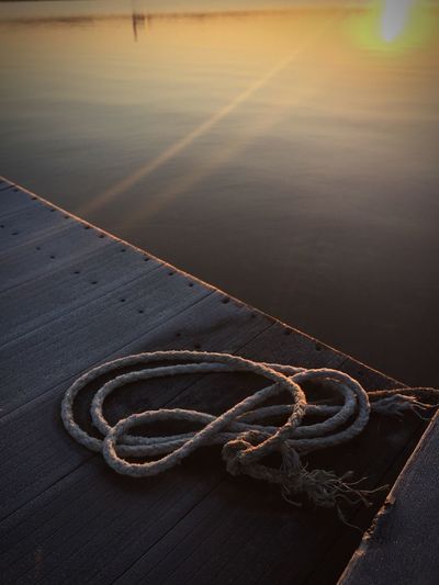 High angle view of rope on jetty over lake during sunset