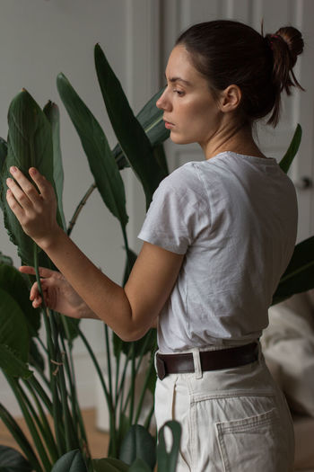 Side view of young woman holding plant