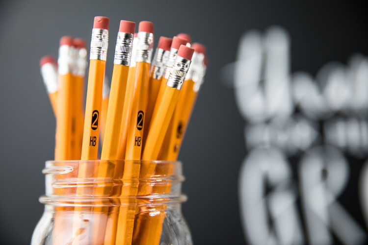 Close-up of pencils in jar against blackboard