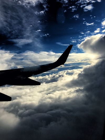 Low angle view of airplane flying over cloudy sky