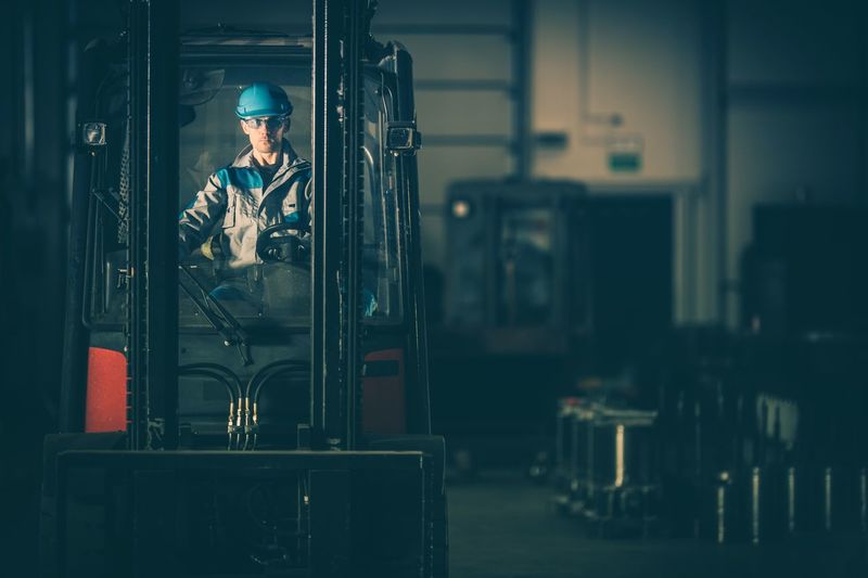 Worker riding forklift in factory