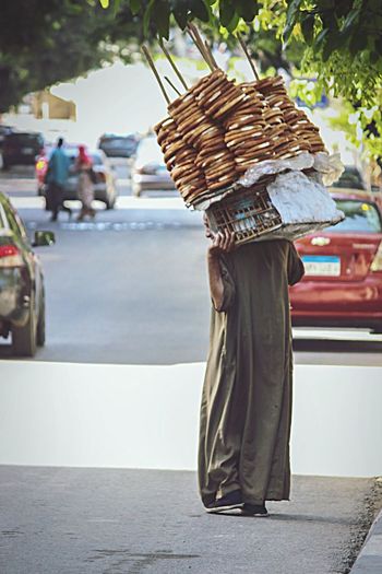 Rear view of man carrying basket on road