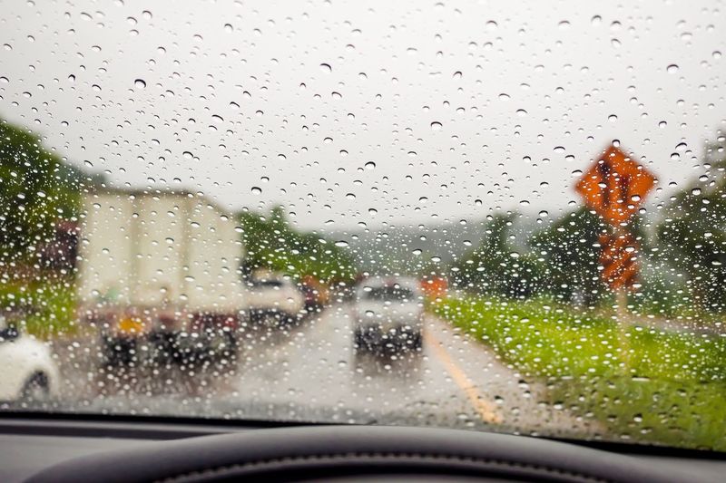 Raindrops on windshield seen through wet glass window