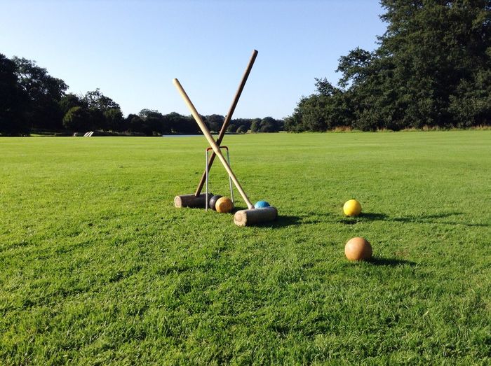 Croquet set on grassy field against sky