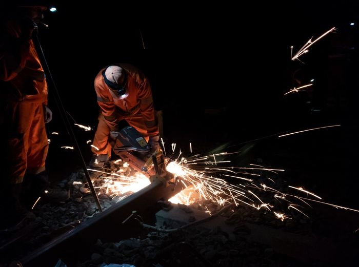 Welders welding railroad track at night