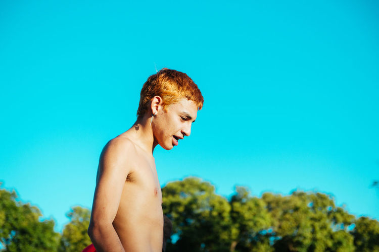 Young man looking away against blue sky