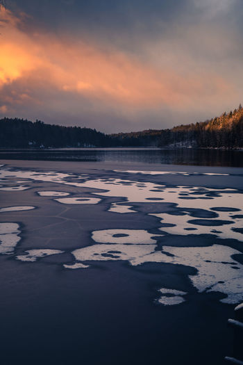 Surface level of frozen lake against sky during sunset