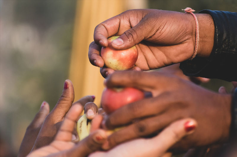 A person giving apples to people from hands to hands in outside close up