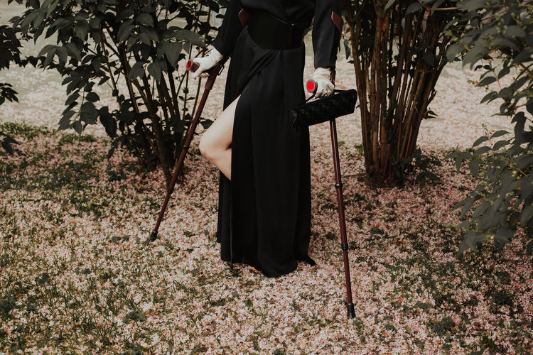 Woman holding crutch while standing outdoors