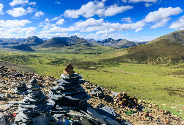 Stack of stones on field against mountain range