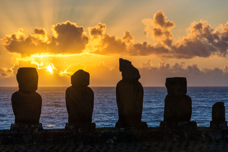 Silhouette ahu tahai statues at easter island against sky during sunset