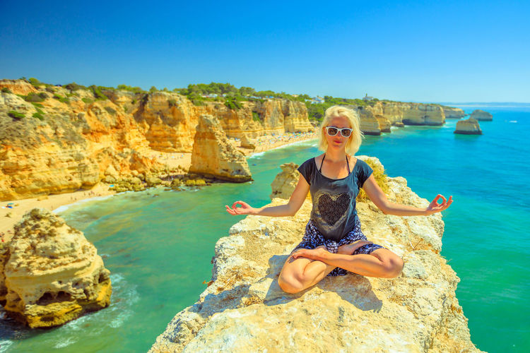 Woman doing yoga on rock at beach