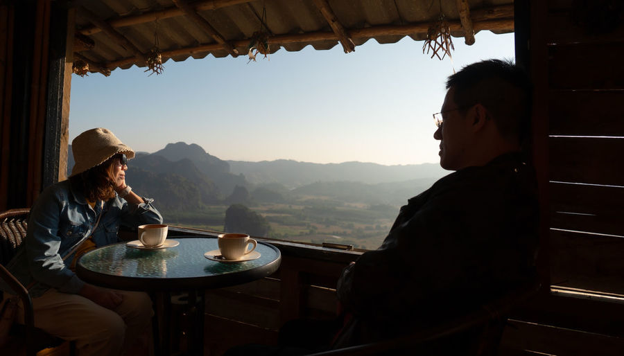 Couple sitting at restaurant against landscape