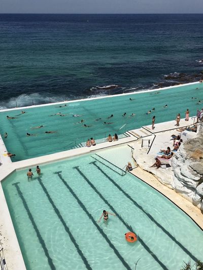 High angle view of people enjoying in infinity pool by sea
