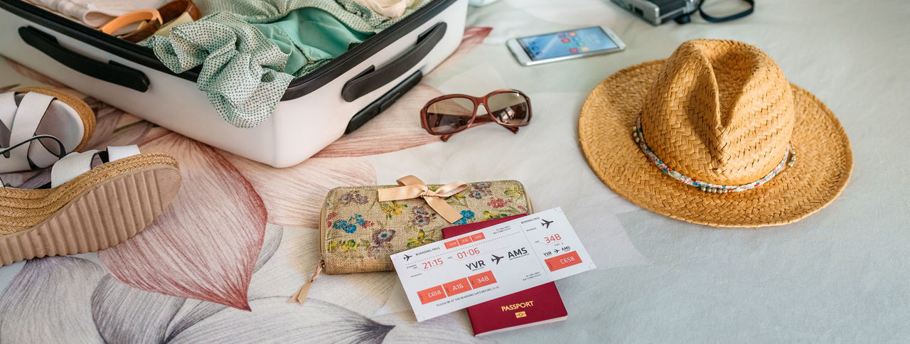 Personal accessories on bed with flight ticket