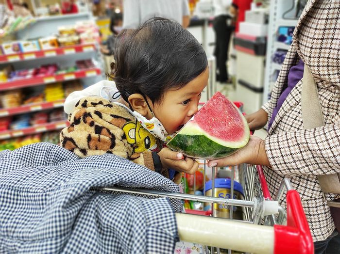 Girl holding watermelon fruit in store