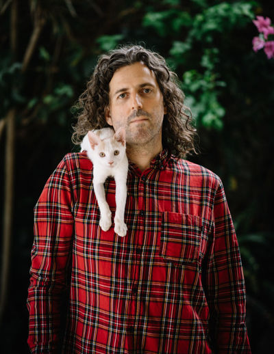 Portrait of man with cat on shoulder outdoors