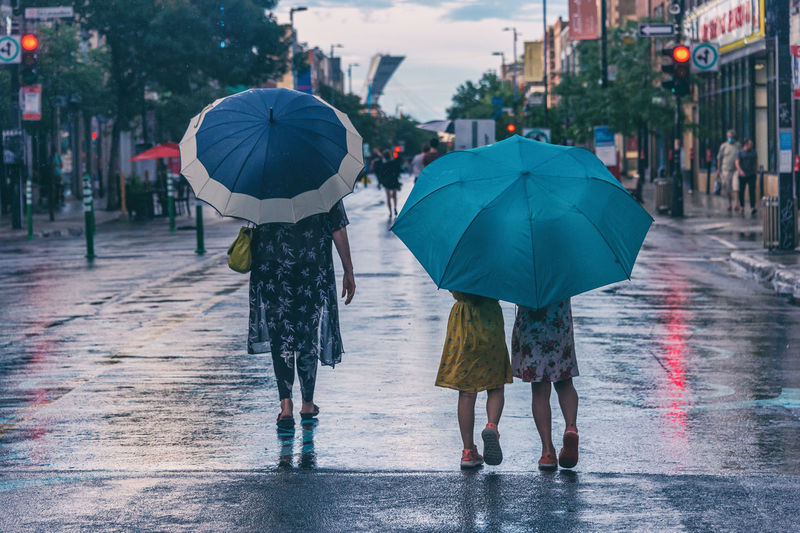 Rear view of people walking on wet street during rainy season