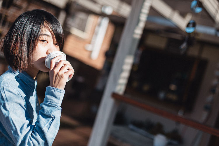 Portrait of woman drinking coffee from disposable cup