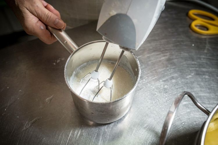 Cropped hand preparing food with wire whisk in kitchen